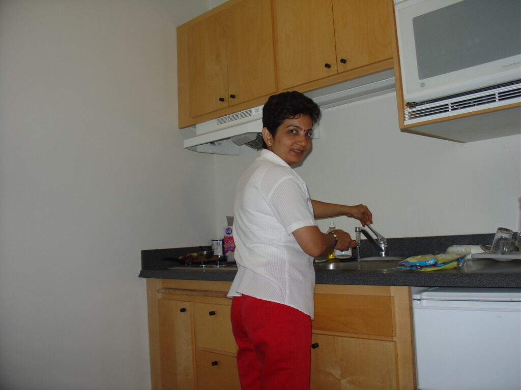 Bhavana Kalantri cooking in the kitchen of Dr. S.P. Kalantri's studio apartment at Manville, Berkeley, December 2004. She prepared several Indian dishes for MPH classmates Christine Ho, Maureen Morgan, and Joseph Ezoua — with minimal utensils in a student kitchen.
