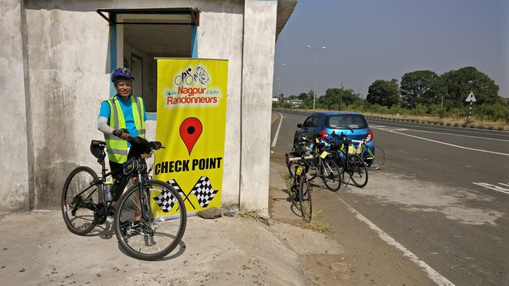 Dr. S.P. Kalantri at the Nagpur Randonneurs checkpoint during his 200 km Brevet, Nagpur to Pandhurna, 2017. High-visibility vest, blue helmet, bicycle beside him.