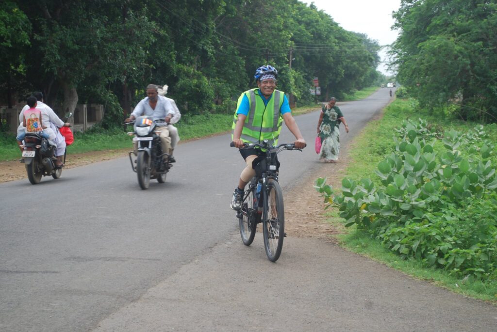 Dr. S.P. Kalantri cycling on the Nagpur–Sevagram road in August 2016, approaching the Sevagram checkpoint during his first 200km Brevet, wearing a high-visibility vest and helmet