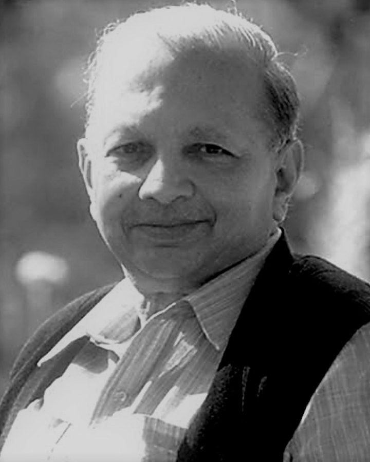 Black and white portrait of Dr. A.P. Jain, former Professor and Head of Medicine at MGIMS Sevagram, smiling warmly.