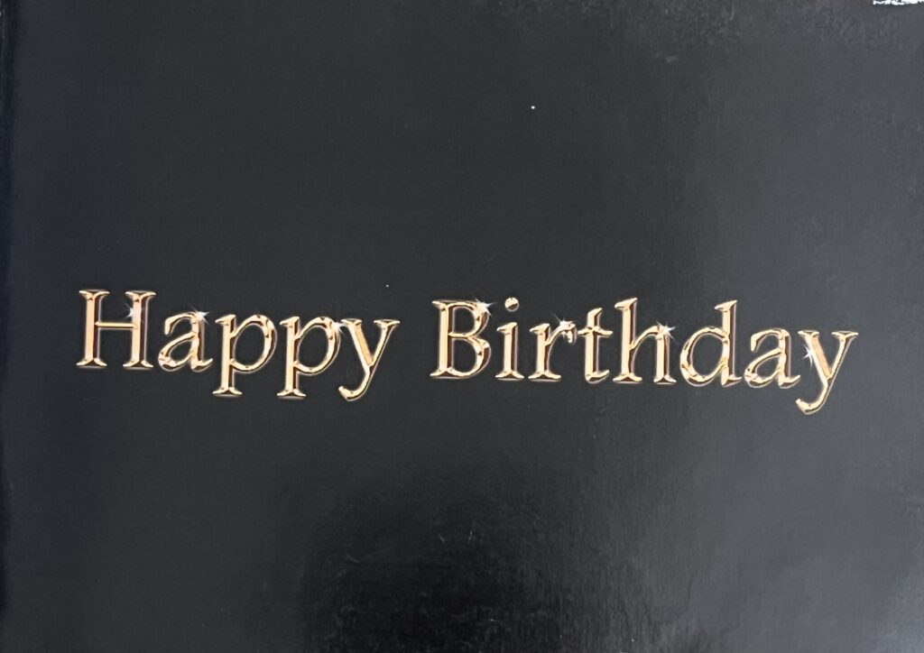 Cover of the black birthday book made by Ashwini, Amrita, and Shaily for SP Kalantri's 50th birthday, August 2007. Gold lettering on black — "Happy Birthday" — designed and printed by his children.